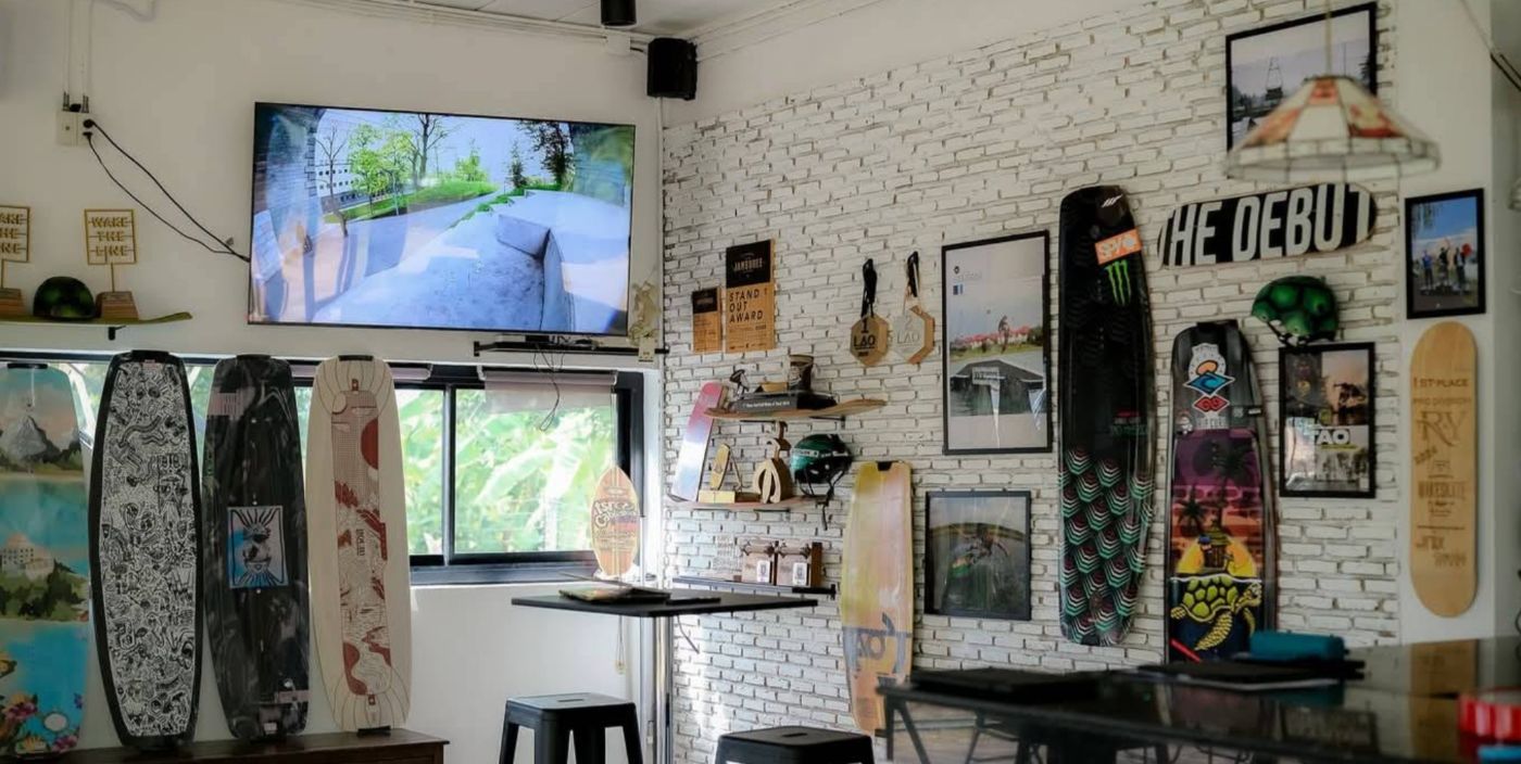 Inside Cafe Tao: wakeboards along a white brick wall, a TV, and bar stools by the window
